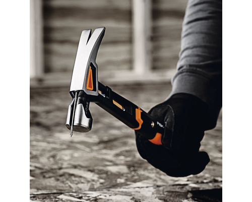 Un meșter ține în mână un ciocan de tâmplar cu un cui.