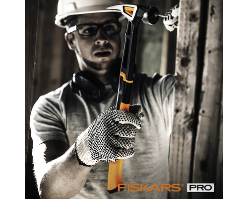 Un bărbat cu cască de protecție folosește un ciocan Fiskars pentru a bate un cui.