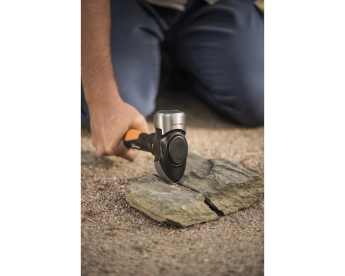 Un bărbat sparge o piatră cu un ciocan de despicat.