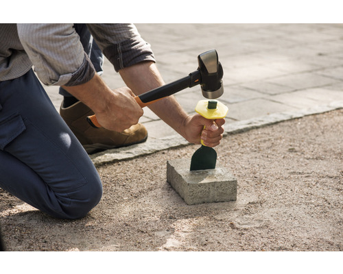 O persoană folosește un ciocan și o daltă pentru a lucra o piatră.