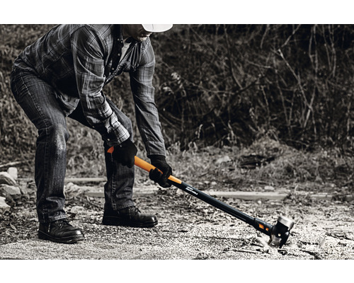 Un bărbat lucrează cu un ciocan de despicat Fiskars în aer liber.