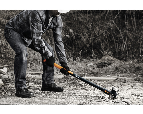 Un bărbat folosește un ciocan de despicat pentru a despica lemne