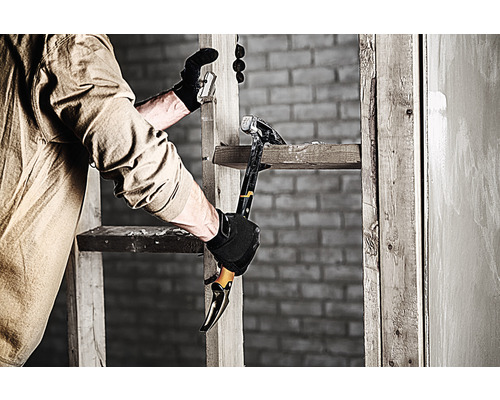 O persoană folosește un ciocan și un levier pe o scară pentru lucrări de demolare.