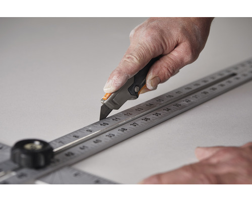 Mână taie material cu cutter și riglă de tăiere