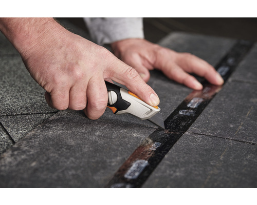 Un cuțit pentru covoare taie un covor de-a lungul unei rigle.