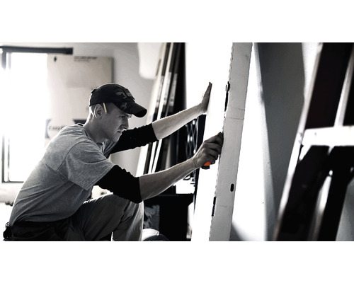 Bărbat lucrând la o ușă cu o unealtă