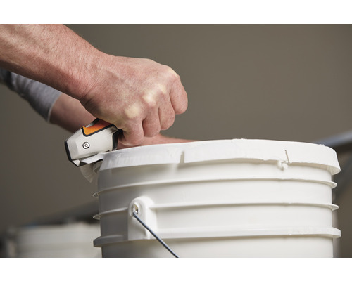 O persoană deschide o găleată cu vopsea cu o unealtă