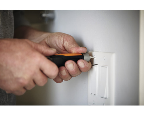 O persoană folosește o șurubelniță pe un întrerupător