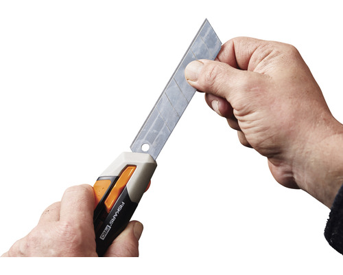 Mâini schimbând lama pe cutterul Fiskars Pro