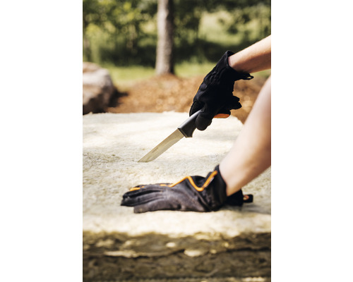 O persoană taie o placă izolatoare cu un cuțit.