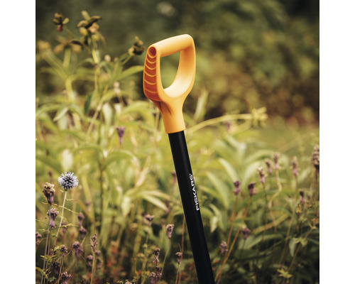 Cazma de grădină Fiskars în fața plantelor