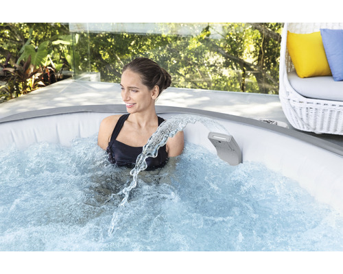 Femeie relaxându-se într-un jacuzzi gonflabil cu cascadă în aer liber.