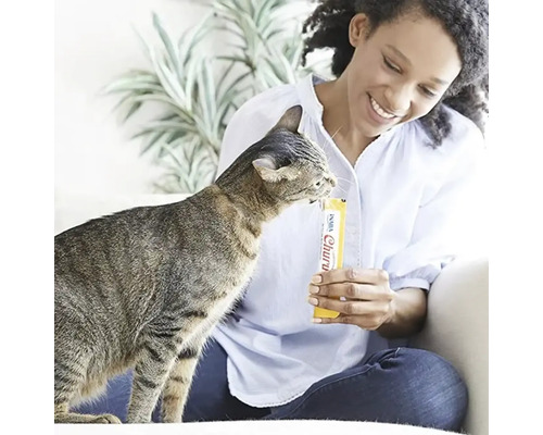 Femeie hrănind o pisică cu o gustare