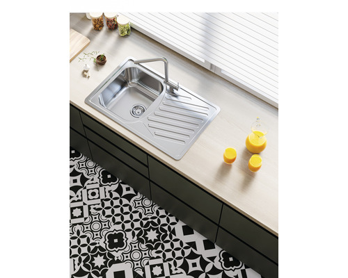 Chiuvetă din oțel inoxidabil cu zonă de scurgere și robinet într-o bucătărie luminoasă.