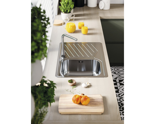 Scenă de bucătărie cu chiuvetă, robinet, tocător și ingrediente pe un blat