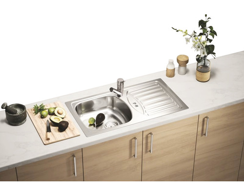 Chiuvetă din oțel inoxidabil cu uscător într-o scenă de bucătărie cu obiecte decorative.