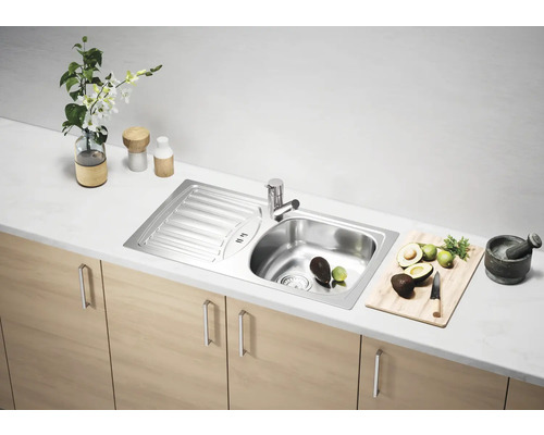 Chiuvetă din oțel inoxidabil cu uscător pe un blat de bucătărie cu avocado, lămâi verzi și mojar