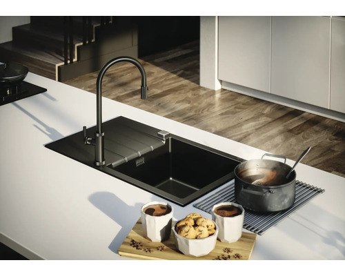 Scenă de bucătărie cu chiuvetă, robinet, oală și veselă pe un blat de bucătărie.