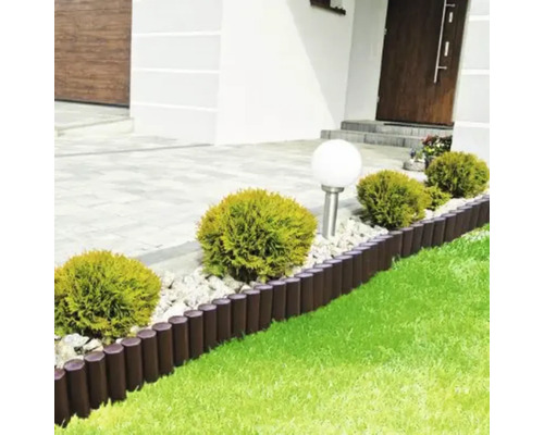 Scenă de grădină cu gazon, pietriș decorativ, bule de buxus și un gard de palisadă pentru delimitarea straturilor de flori