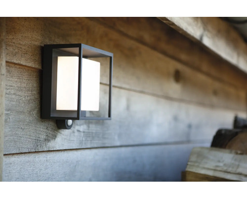 Lumină de perete exterioară pătrată cu senzor de mișcare pe un perete de lemn