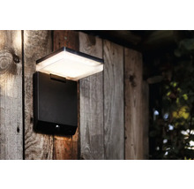 Lumină de perete LED neagră pentru exterior cu senzor de mișcare pe un perete de lemn