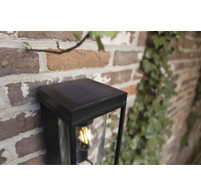 Lampă solară cu abajur transparent pe perete de cărămidă