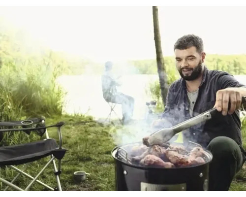 Bărbat care face grătar cu carne afară cu clești de grătar
