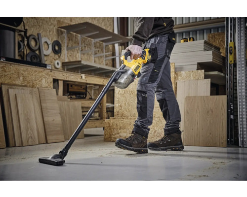Un muncitor folosește un aspirator fără fir DeWalt într-un atelier.
