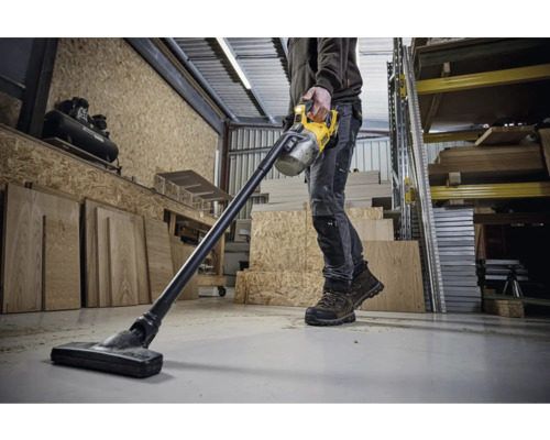 Un bărbat folosește un aspirator fără fir DeWalt într-un atelier.
