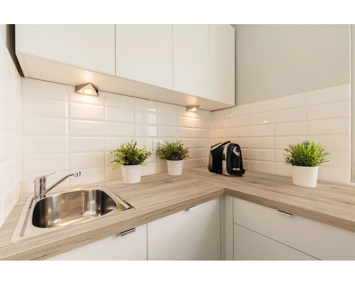 Chiuvetă de bucătărie cu robinet, blat și decorațiuni într-o bucătărie luminoasă.