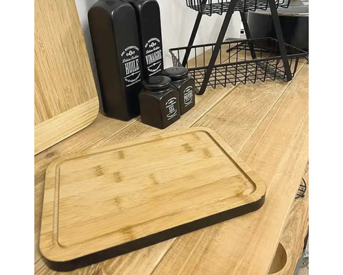 Aranjament decorativ cu tocătoare, sticle de ulei și oțet, recipiente pentru condimente și un etajer pe o masă de lemn.