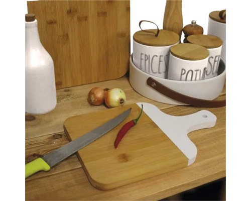 Scenă de bucătărie cu tocătoare, condimente, ceapă, ardei iute și cuțit pe o masă de lemn.