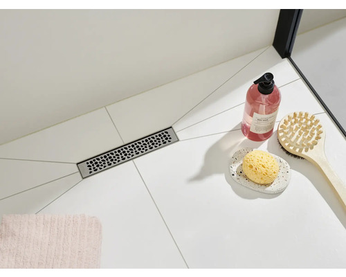 Baie cu rigolă de duș, săpun și perie de baie pe gresie deschisă la culoare