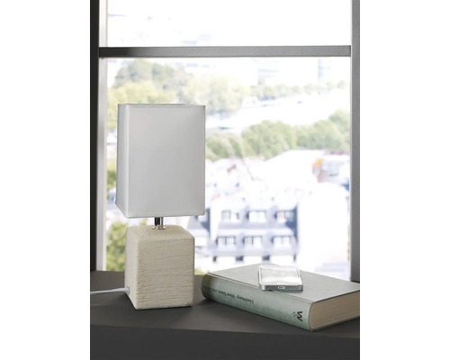 Lampă de masă decorativă cu abajur pătrat și bază pe o masă lângă o carte