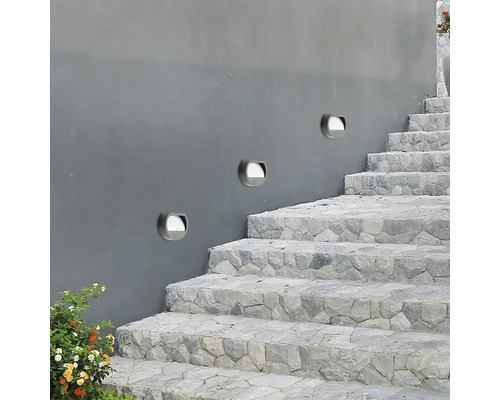 Trei lămpi de perete pe un zid gri lângă o scară de piatră