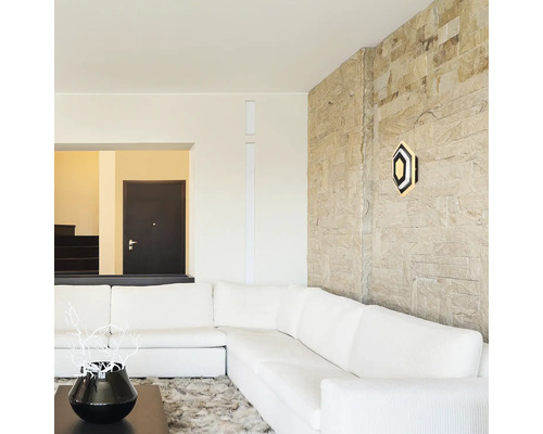 Living luminos cu canapea de colț albă, scară de piatră și veioză hexagonală de perete