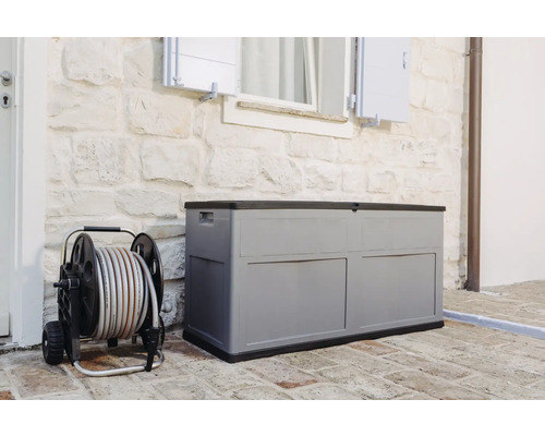 Ladă de grădină gri din plastic lângă un cărucior pentru furtun