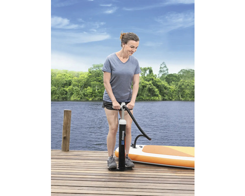 Femeie umflând o placă stand-up paddle cu o pompă manuală pe un ponton de lemn