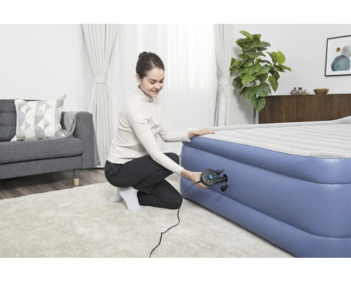 Femeie umflă o saltea pneumatică cu o pompă de aer.