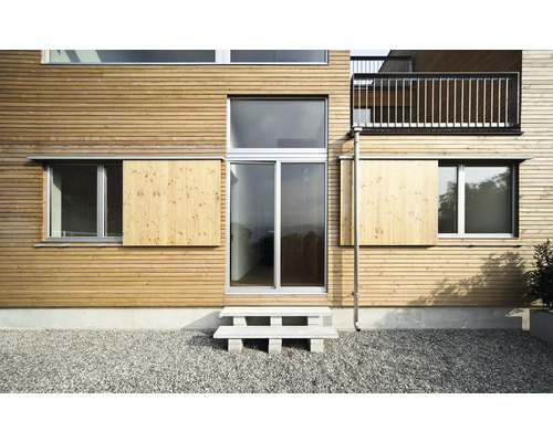 Fațada unei case cu placare din lemn, ferestre și o scară exterioară