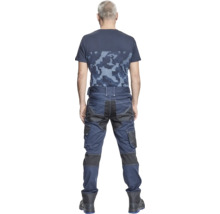 O persoană poartă pantaloni de lucru albaștri și un tricou cu camuflaj din spate.
