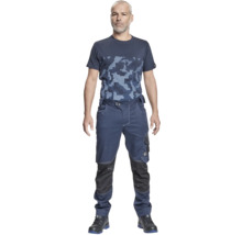 Bărbat purtând pantaloni de lucru albaștri cu buzunare pentru genunchiere și un tricou cu model de camuflaj.
