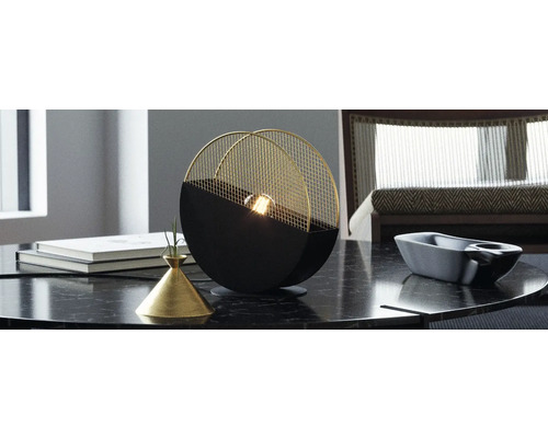 Lampă de masă decorativă cu bază neagră și abajur auriu pe o masă