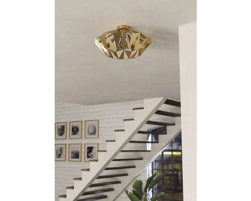 Plafonieră aurie cu design geometric într-o cameră luminoasă