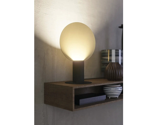 Lampă de masă cu abajur rotund pe o poliță de lemn