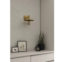 Lampa de perete de culoare aurie deasupra unei comode albe cu decorațiuni