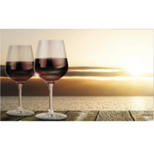 Două pahare de vin cu vin roșu pe o masă de lemn în fața mării la apus