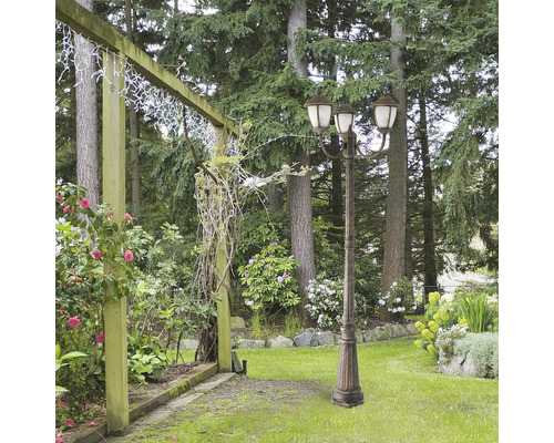 Peisaj de grădină cu un felinar decorativ de grădină cu trei brațe.