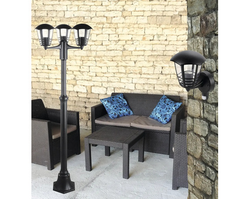 Scenă cu un corp de iluminat exterior negru, un corp de iluminat negru pentru căi de acces cu trei capete de iluminat și mobilier de grădină pe o terasă
