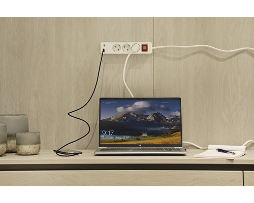 Laptop, smartphone și prelungitor pe un birou.